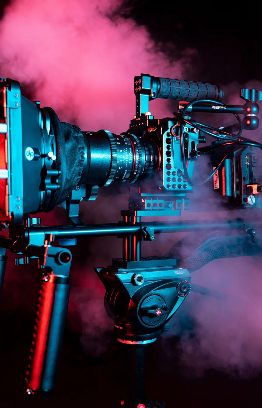 Una cinepresa professionale illuminata da fumo colorato su fondo scuro